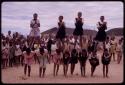 Girls standing on the backs of others, imitating horses, playing a game at recess at a school