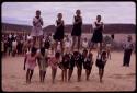 Girls standing on the backs of others, imitating horses, playing a game at recess at a school