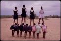 Girls standing on the backs of others, imitating horses, playing a game at recess at a school