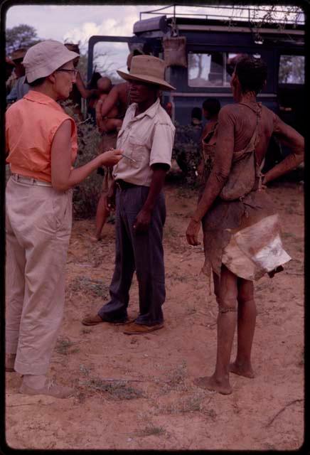 Man and a woman talking with Lorna Marshall in front of the expedition Land Rover