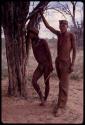 Two men standing next to a tree