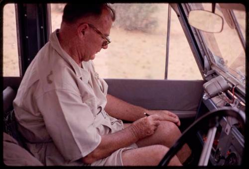 C. J. Mathias sitting in an expedition truck, writing a word game on his leg