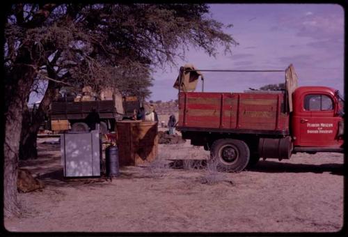 Refrigerator and drums next to an expedition truck (Dodge) in camp