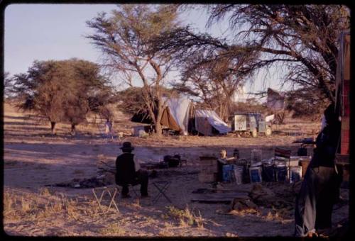 Expedition member sitting in a camp along the Nossob River, view from behind