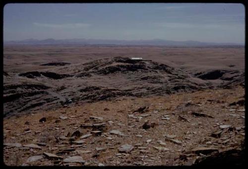 Landscape, stony ground and farmhouse in the distance