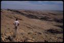 Leslie McIntyre standing back to camera, showing rocky landscape