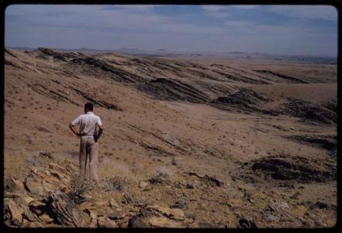 Leslie McIntyre standing back to camera, showing rocky landscape