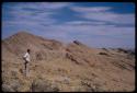 Leslie McIntyre standing, showing rocky landscape