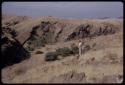 Landscape of a dry riverbed, rocks and hills; Leslie McIntyre standing to the side