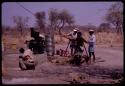 Group of people building a water pump; ǂToma and /Gao pulling on a rope and Kernel Ledimo kneeling by the cement base