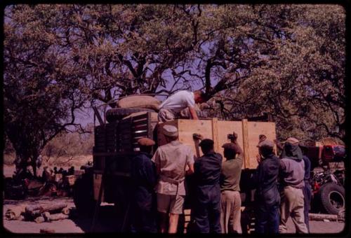 Kurt Ahrens on truck, other expedition members standing around the truck