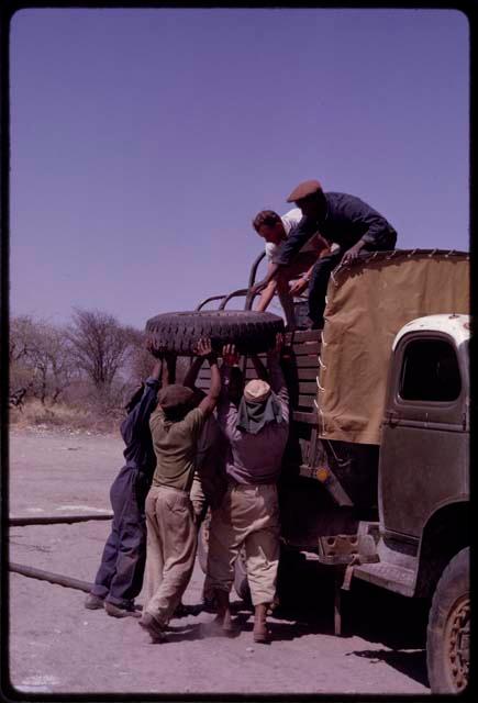 O.P.M. Prozesky, Kurt Ahrens, and other expedition members loading a wheel into a truck