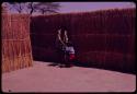 Person standing with Kernel Ledimo's child in front of a fence