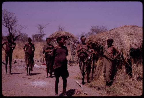 Group standing before ǂToma's hut, includes ǂToma and !U