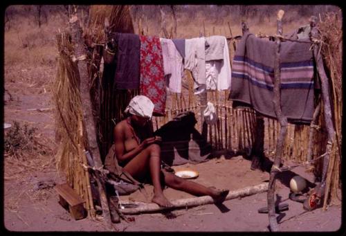 Wife of "ǂGao Lame" sitting in an unfinished hut