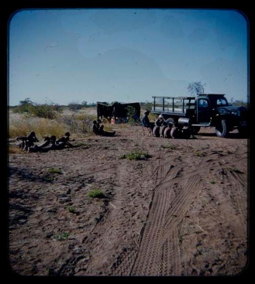 Expedition: Expedition members (including Lorna Marshall) and men having a sound recording session by a truck, seen from a distance