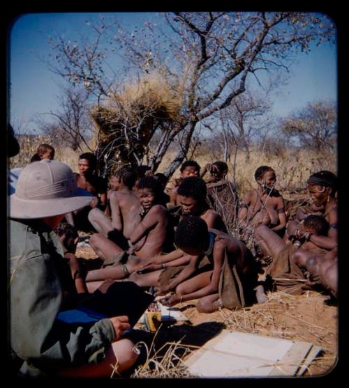 Expedition: Child using crayons and Elizabeth Marshall Thomas taking notes, with a group of people in the background