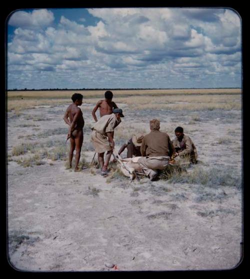 Expedition: John Marshall, Ngani, and other people gathered around a dead animal on the ground