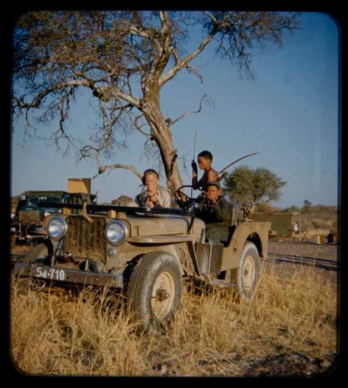 Expedition: Ngani driving Jeep, with John Marshall holding a camera and //Ao with hunting equipment