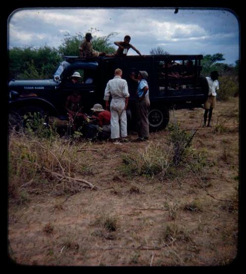 Expedition: John Marshall, Ngani, and other men gathered near a truck to repair a flat tire on their trip from "Kubi"