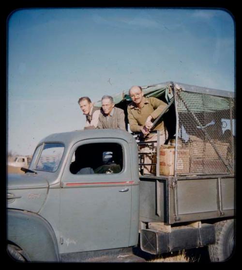 Expedition: Three men standing in the back of a truck on their trip from "Kubi"