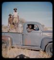 Expedition: Four men in an expedition truck; two men are sitting in the front and the other two standing in the back, on their trip from "Kubi"