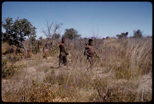 Oukwane and Gai walking through grass, other people in background