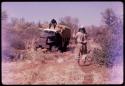 Expedition member sitting on the top of a truck, with another man standing facing him