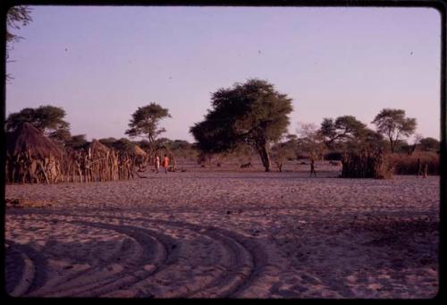 Expedition truck tracks in Urobitsi's area, with huts and people in the background