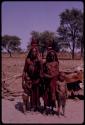 Wareka (wife of Berani) and Kavenavo (wife of Dauku) wearing pre-colonial (“traditional”) Herero dress, standing with two children