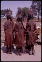 Three women wearing pre-colonial (“traditional”) Herero dress, seen from behind