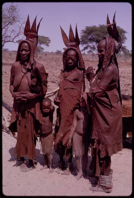 Wareka (wife of Berani), Kavenavo (wife of Dauku), and Sangorutenda (daughter of Wareka) wearing pre-colonial (“traditional”) Herero dress, standing with two children