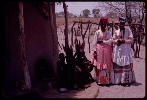 Young women wearing "modern" Herero dresses and women wearing "traditional" Herero dress (one of them is probably Thikithe, a daughter of Wareka) sitting nearby