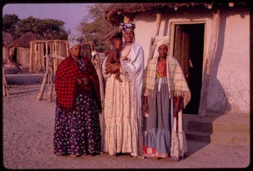 Three women (one of  Lukas' wives, Kaungura, and probably Tatoo or Nandavitho) standing; Kaungura is holding a baby