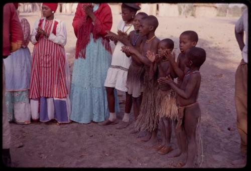 Women wearing "modern" Herero dress, with girls singing and clapping