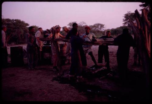 Group of people filling water barrels at Urobitsi's well, with a winch hauling up a bucket