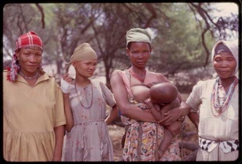 Woman holding a baby and two other women standing at the expedition camp