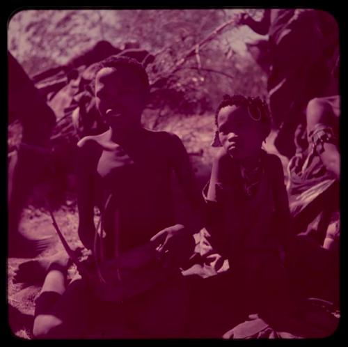 Music: /Gishay (Gau's son) sitting and playing a //guashi, with a girl sitting next to him