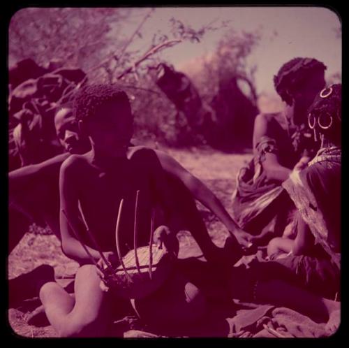 Music: /Gishay (Gau's son) playing a //guashi, sitting with a group of people