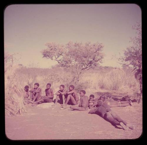 Music: "/Gao Music" playing a //guashi, sitting with a group of men including //Ao, !Naishi (his brother) and "Old Demi" lying down