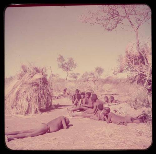 Music: "/Gao Music" playing a //guashi, sitting with a group of men including //Ao, !Naishi (his brother), Tsamgao and "Old Demi" lying down