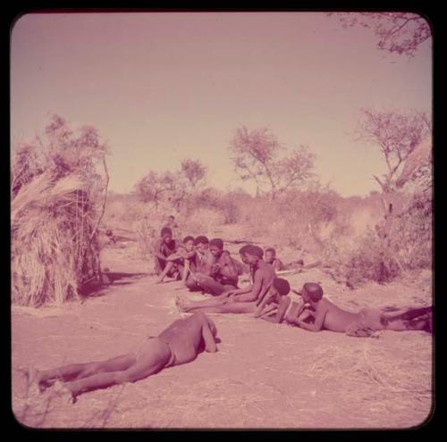 Music: "/Gao Music" playing a //guashi, sitting with a group of men including //Ao, !Naishi (his brother), Tsamgao and "Old Demi" lying down