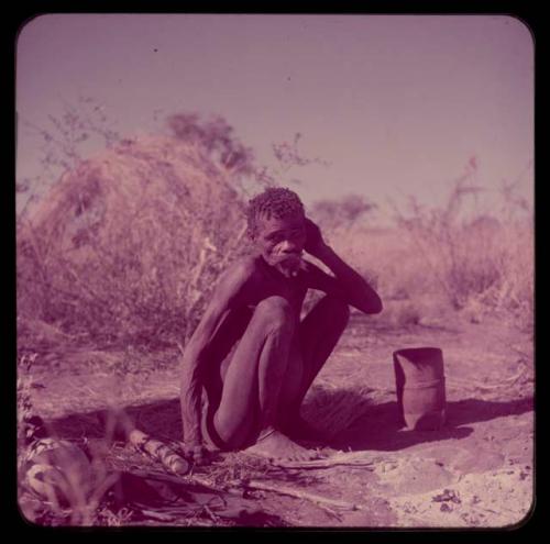 Portraits: "Old /Gishay" sitting, with a mortar on the ground in front of him, skerm in the background