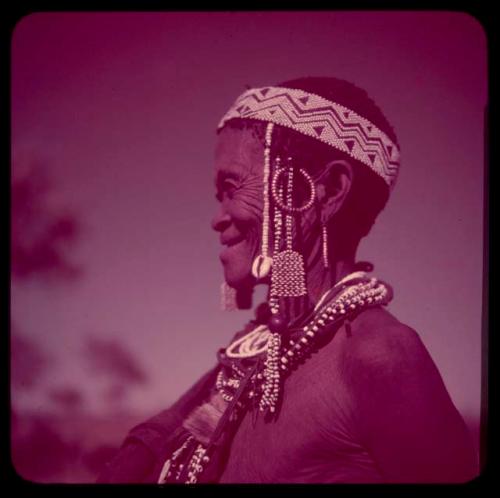 Portraits: "Old /Gam" wearing ornaments, including cowrie shells and a headdress of European beads, profile