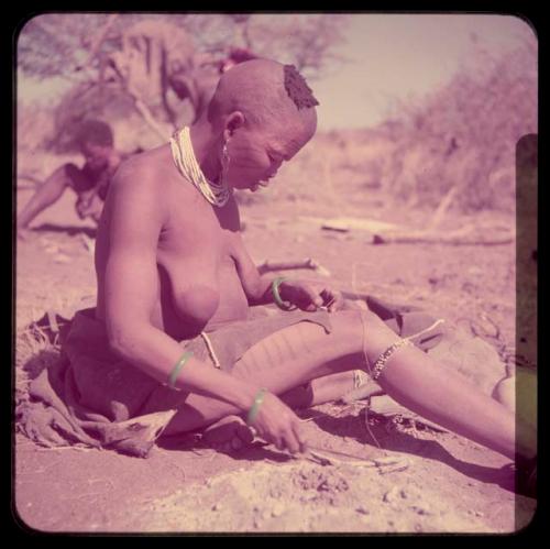 Sewing: !Ungka sewing beads on a piece of leather, with scarification visible on her leg