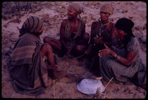 Women playing dandiri, including N/kxabe (daughter of /Oβa) with her foot on the stick, Tomku, Dadum, and ǂKxoba