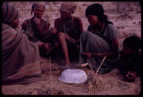 Women playing dandiri, including N/kxabe (daughter of /Oβa), Tomku, Dadum, and ǂKxoba striking the string with a stick