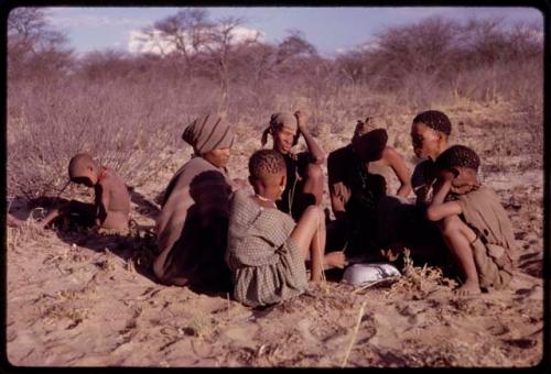 Women playing dandiri, including N/kxabe (daughter of /Oβa), Tomku, Dadum, and ǂKxoba, with two children sitting with them