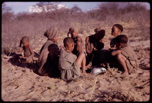 Women playing dandiri, including N/kxabe (daughter of /Oβa), Tomku, Dadum, and ǂKxoba, with two children sitting with them