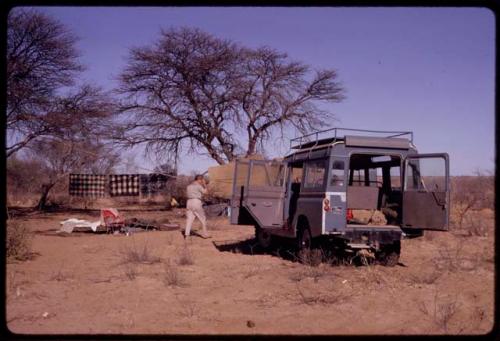 Expedition member walking near the expedition Land Rover, view from behind